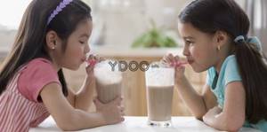две девочки пьют какао через трубочку