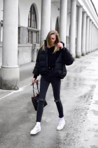 an all-black look with a T-shirt, ripped jeans, a cropped puffer jacket, white sneakers and socks